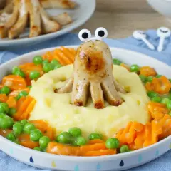 Ein lustiges gesundes Abendessen für Kinder: Würstchen-Oktopus auf Kartoffelbrei mit Erbsen und Karotten.
