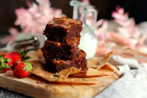 Gestapelte Brownies mit Nüssen und Schokostückchen, dazu frische Erdbeeren. Ein köstliches brownie rezept zum Genießen.