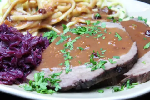 Sauerbraten rezept: Zarte Scheiben Braten mit dunkler Soße, dazu Rotkohl und Spätzle. Ein Klassiker der deutschen Küche.