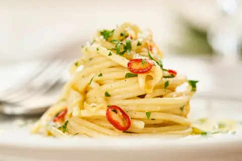 Ein Berg von Spaghetti Aglio e Olio, garniert mit frischer Petersilie und scharfen Chilischeiben.