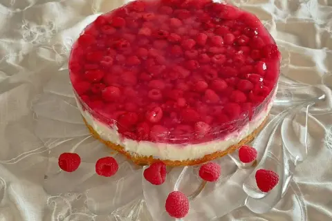 Himbeer-Curd-Torte mit frischen Himbeeren und glänzender Tortenguss-Schicht auf einem cremigen Boden. Ein Genuss für Augen und Gaumen.