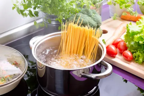 Spaghetti kochen in sprudelndem Wasser. Daneben frisches Gemüse wie Brokkoli, Karotten und Tomaten. So einfach ist es, wie koche ich nudeln!