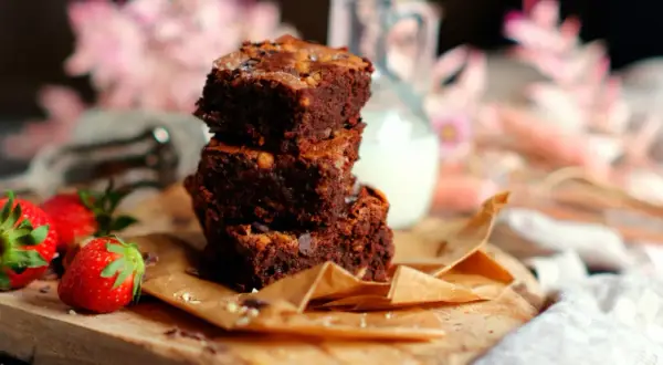 Gestapelte Brownies mit Nüssen und Schokostückchen, dazu frische Erdbeeren. Ein köstliches brownie rezept zum Genießen.