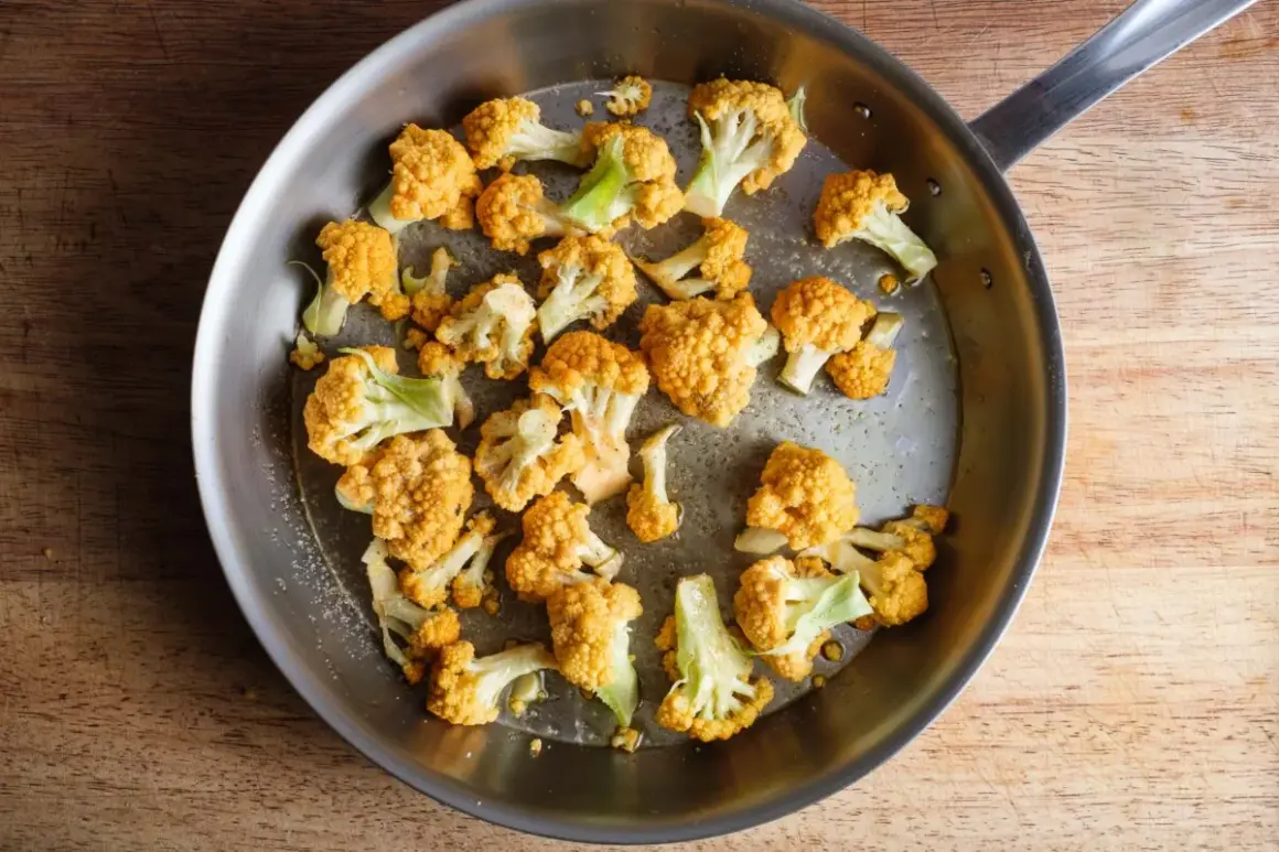 Orangefarbener Blumenkohl wird in einer Pfanne gebraten, um ihn zu kochen.