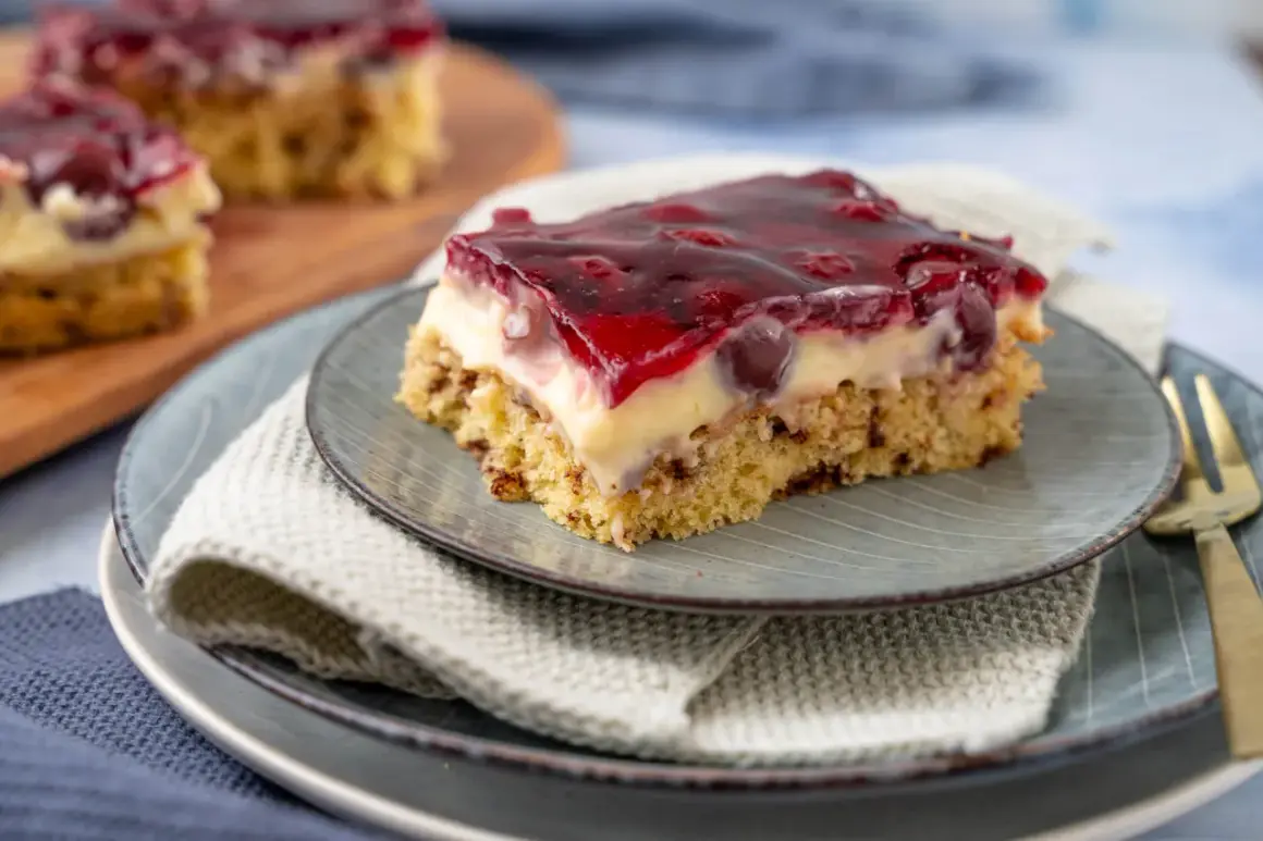 Ein Stück saftige Kirschtorte mit Pudding und Kirschen, bedeckt mit rotem Tortenguss.