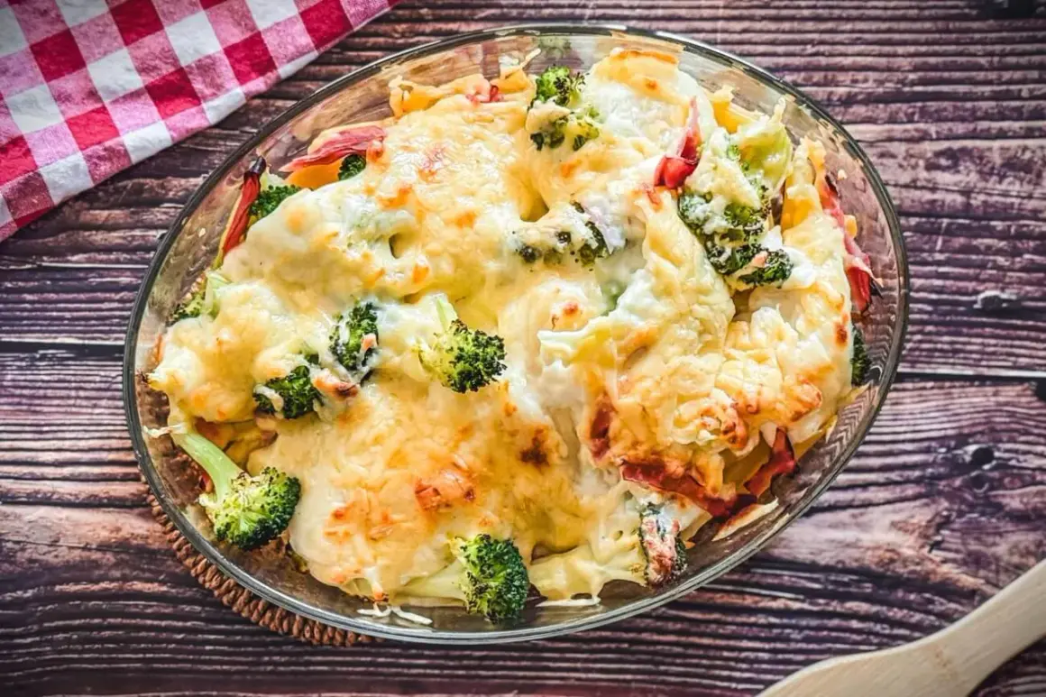 Herzhafter Brokkoli Nudel Auflauf mit geschmolzenem Käse, serviert in einer Glasschüssel auf einem Holztisch.