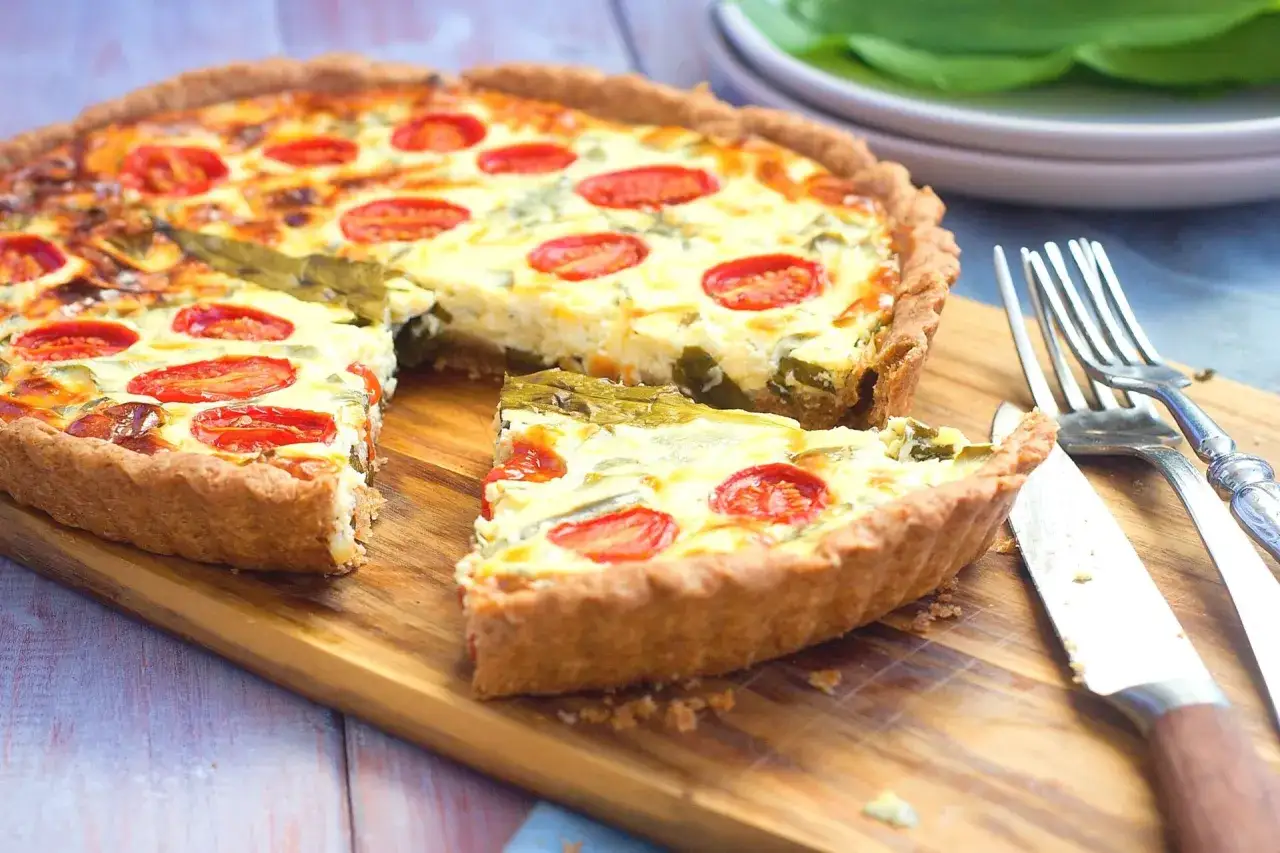 Herzhafte Quiche mit Tomaten und gr&uuml;nem Gem&uuml;se, perfekt f&uuml;r leckere Quiche Rezepte. Ein St&uuml;ck wurde bereits entnommen.