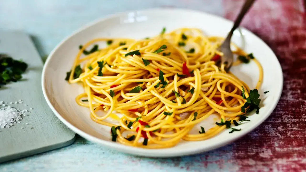 Ein Teller mit k&ouml;stlichen Spaghetti Aglio e Olio, garniert mit Petersilie und Chili.