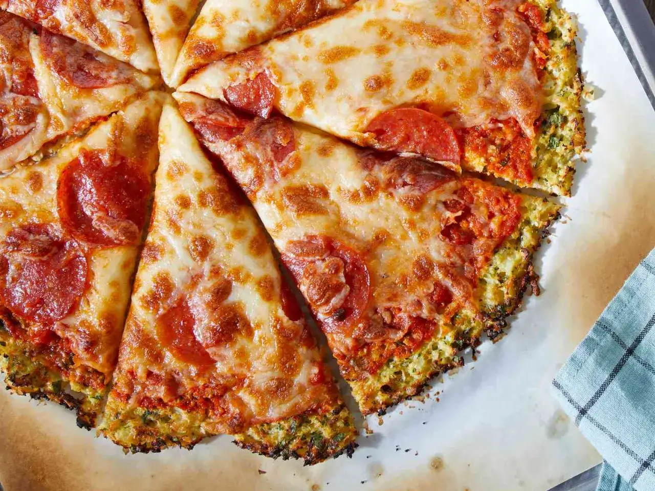 Eine k&ouml;stliche blumenkohl pizza vegan mit geschmolzenem K&auml;se und Pepperoni-Scheiben, auf einem Backblech serviert.