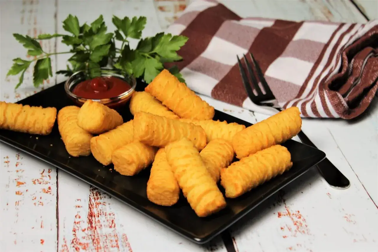 Goldbraune Kroketten, frisch zubereitet, liegen auf einem schwarzen Teller. Dazu gibt es Ketchup und Petersilie. Perfekt zum kroketten selber machen!