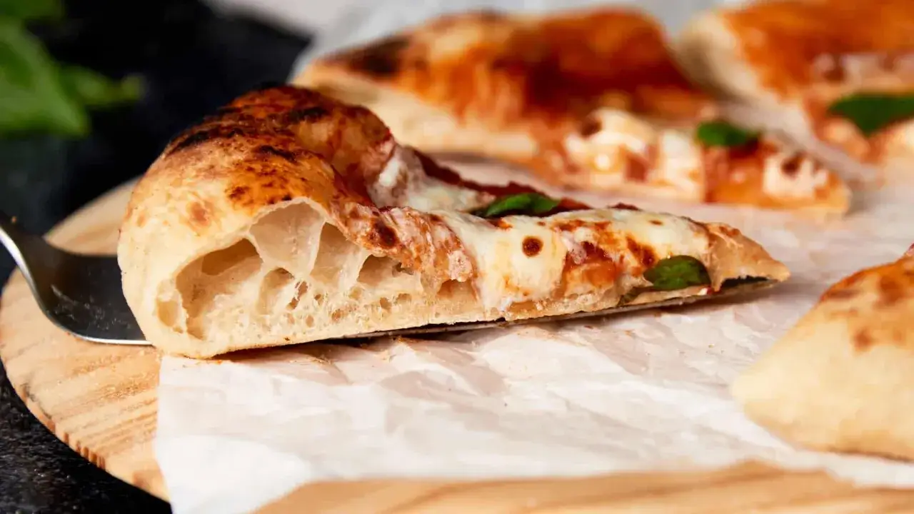 Ein Stück neapolitanische Pizza mit luftigem Rand, geschmolzenem Käse und Tomatensauce. Perfekt für ein authentisches neapolitanische Pizza Rezept.