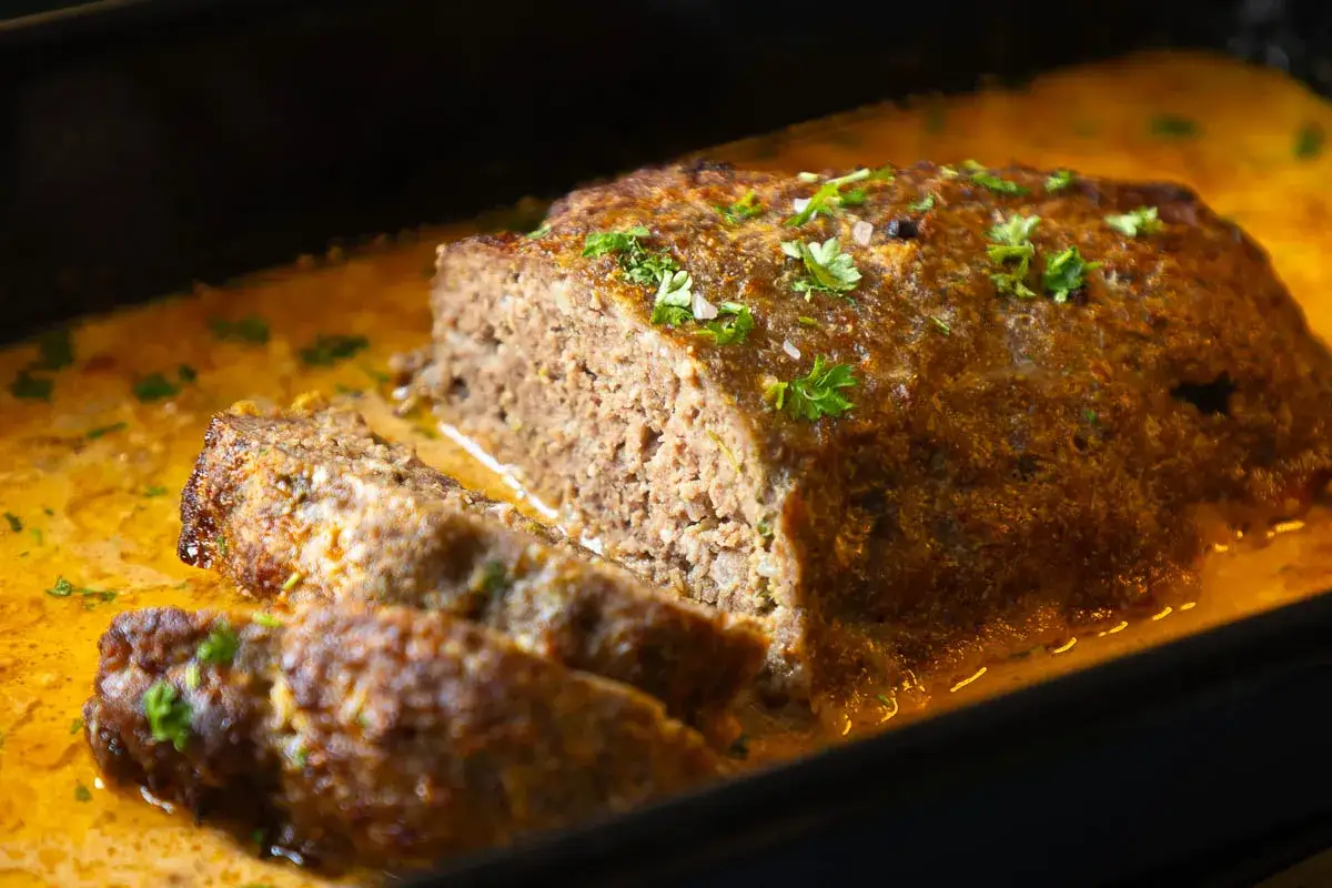Saftiger Hackbraten im Sud, perfekt f&uuml;r ein herzhaftes Hackbraten Rezept. Mit frischer Petersilie garniert.