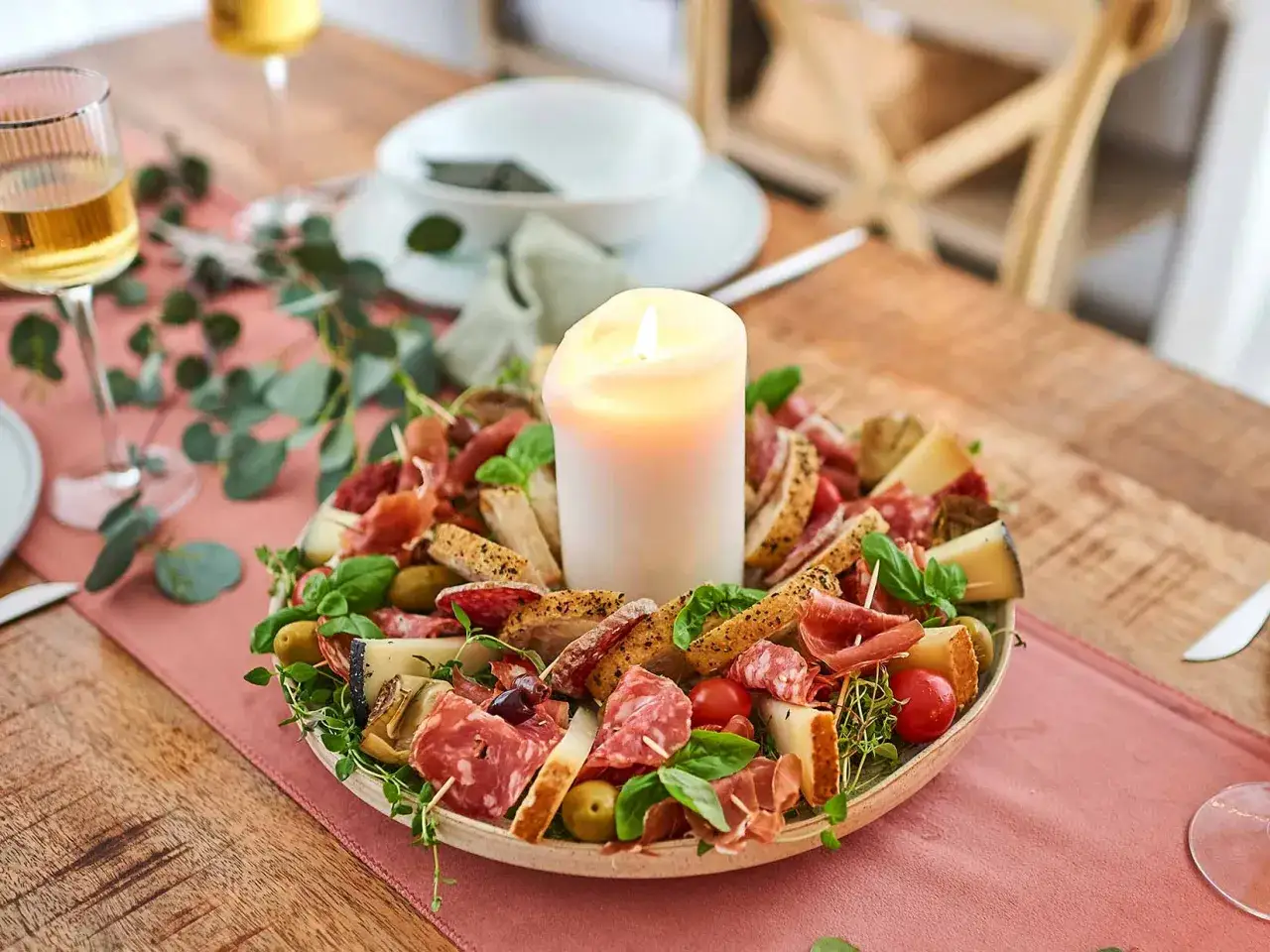 Eine festliche antipasti platte mit Wurst, K&auml;se, Oliven, Brot und Kr&auml;utern, umgeben von einer Kerze.