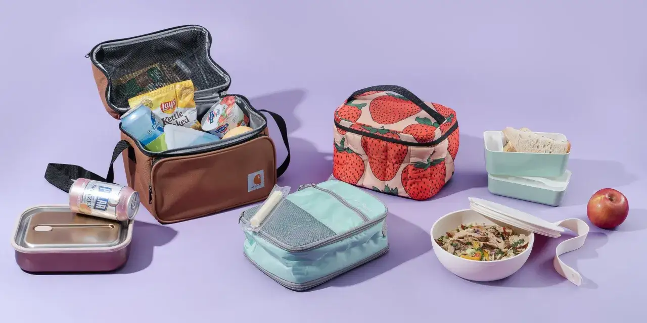 Mehrere Lunchboxen und K&uuml;hltaschen sind bereit f&uuml;r Essen zum Mitnehmen. Darin sind Snacks, Getr&auml;nke und eine Mahlzeit.